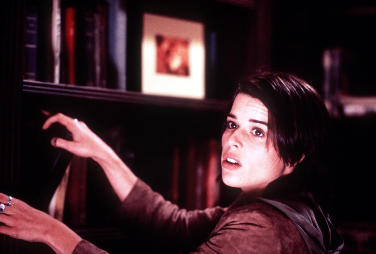 Neve Campbell looks up as she searches through a bookshelf in ‘Scream 3’