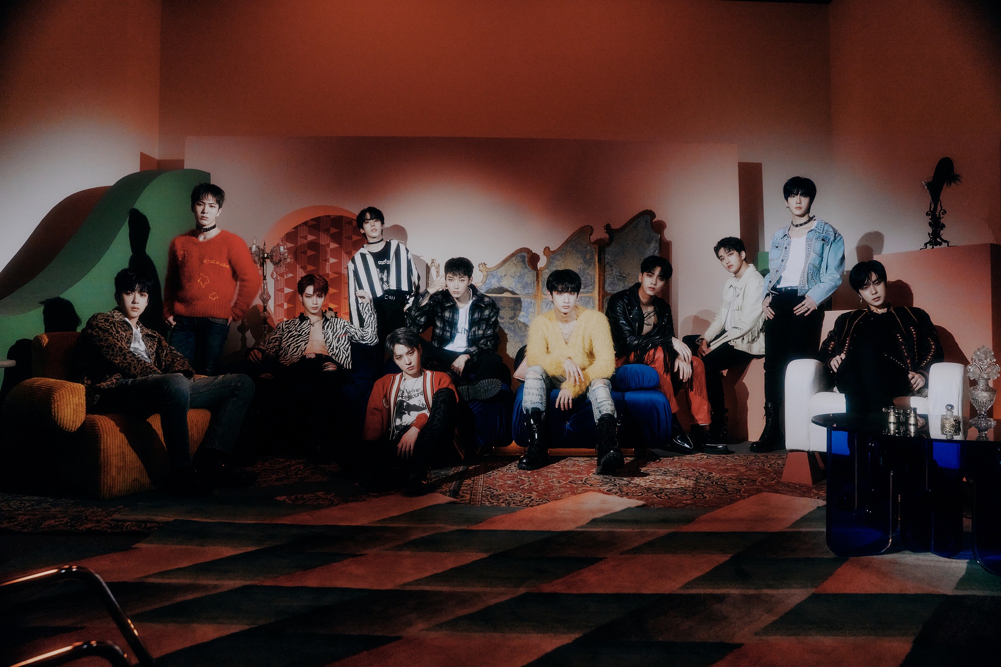 The members of Omega X pose sit in a dim room with red lighting