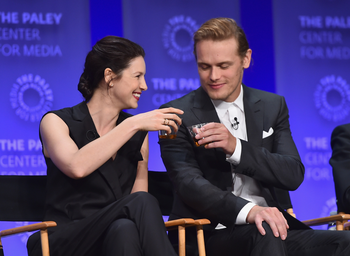 Outlander stars Caitriona Balfe and Sam Heughan cheers with a dram of whiskey at Paleyfest in 2015