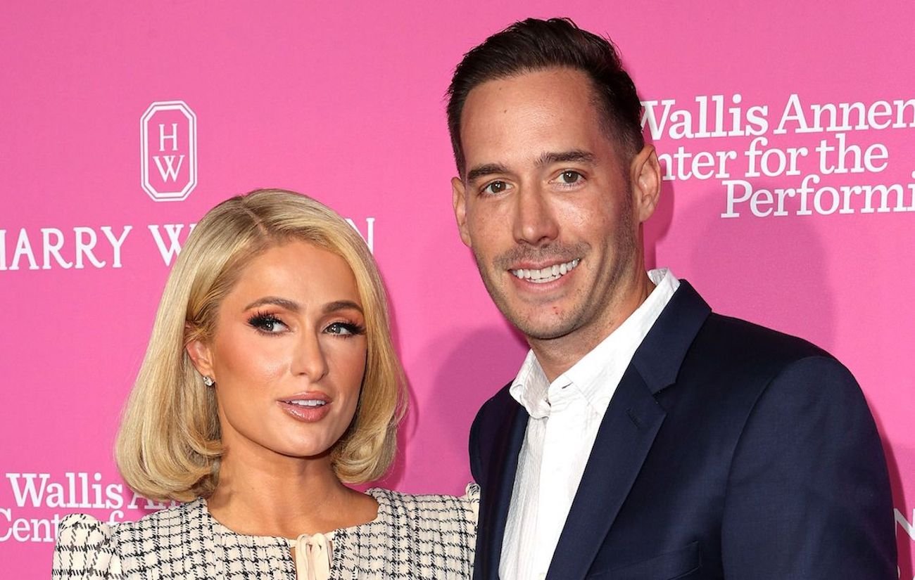 Paris Hilton and Carter Reum smile for photographers standing in front of a pink background