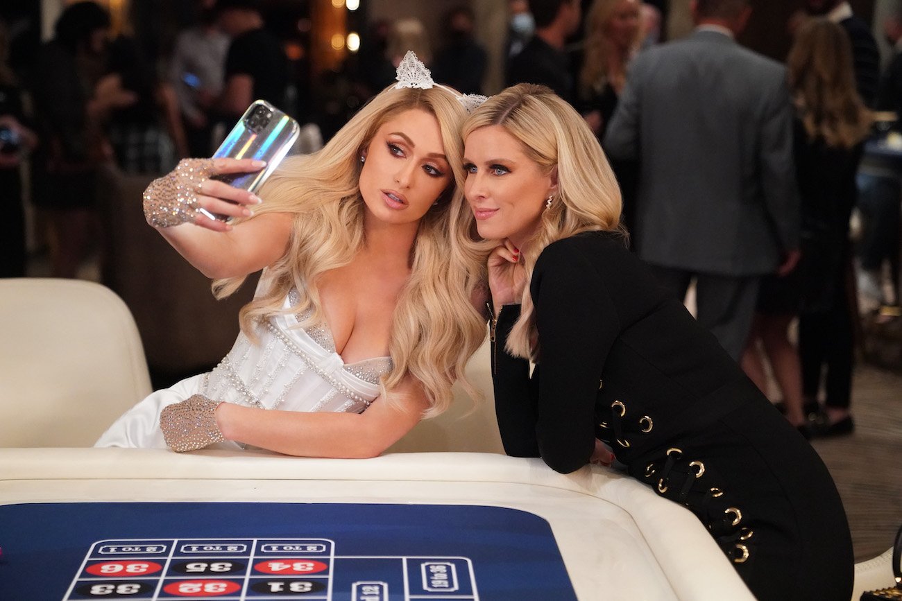 Paris Hilton holds a phone as she and Nicky Hilton Rothschild pose