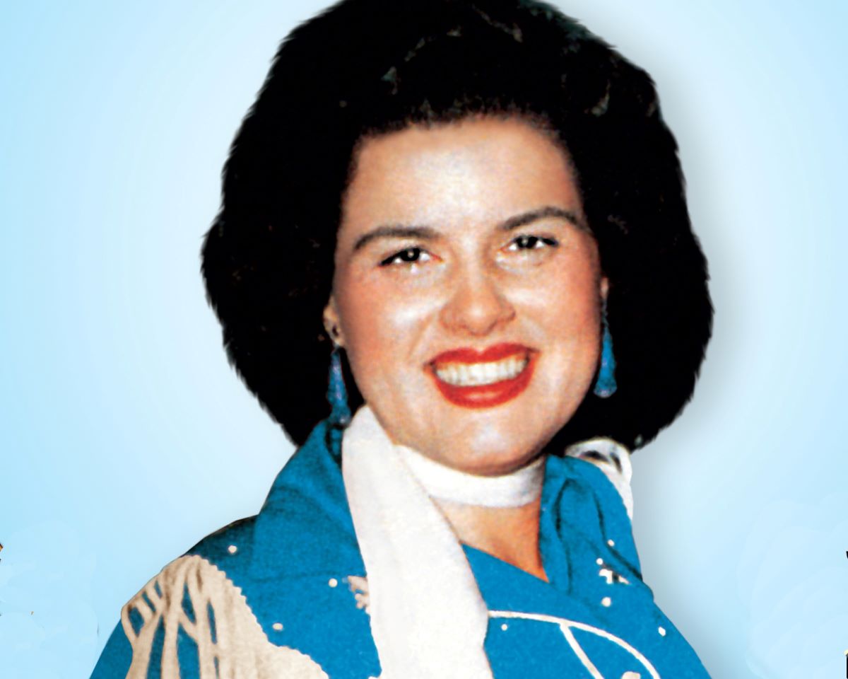 Patsy Cline smiles in blue, with a white scarf and red lips c. 1960