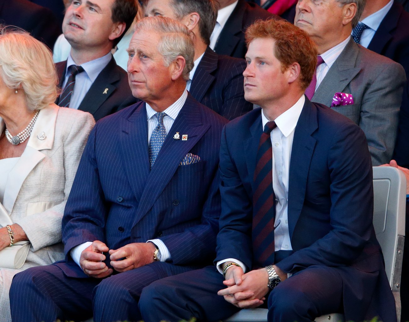 Prince Charles and Prince Harry wearing suits, sitting side by side, looking on