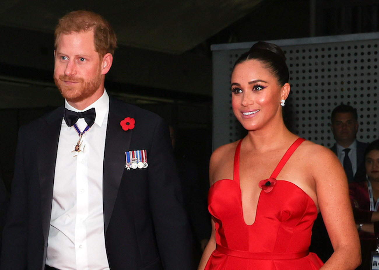 Prince Harry wears a tuxedo as he walks next to Meghan Markle in a red gown