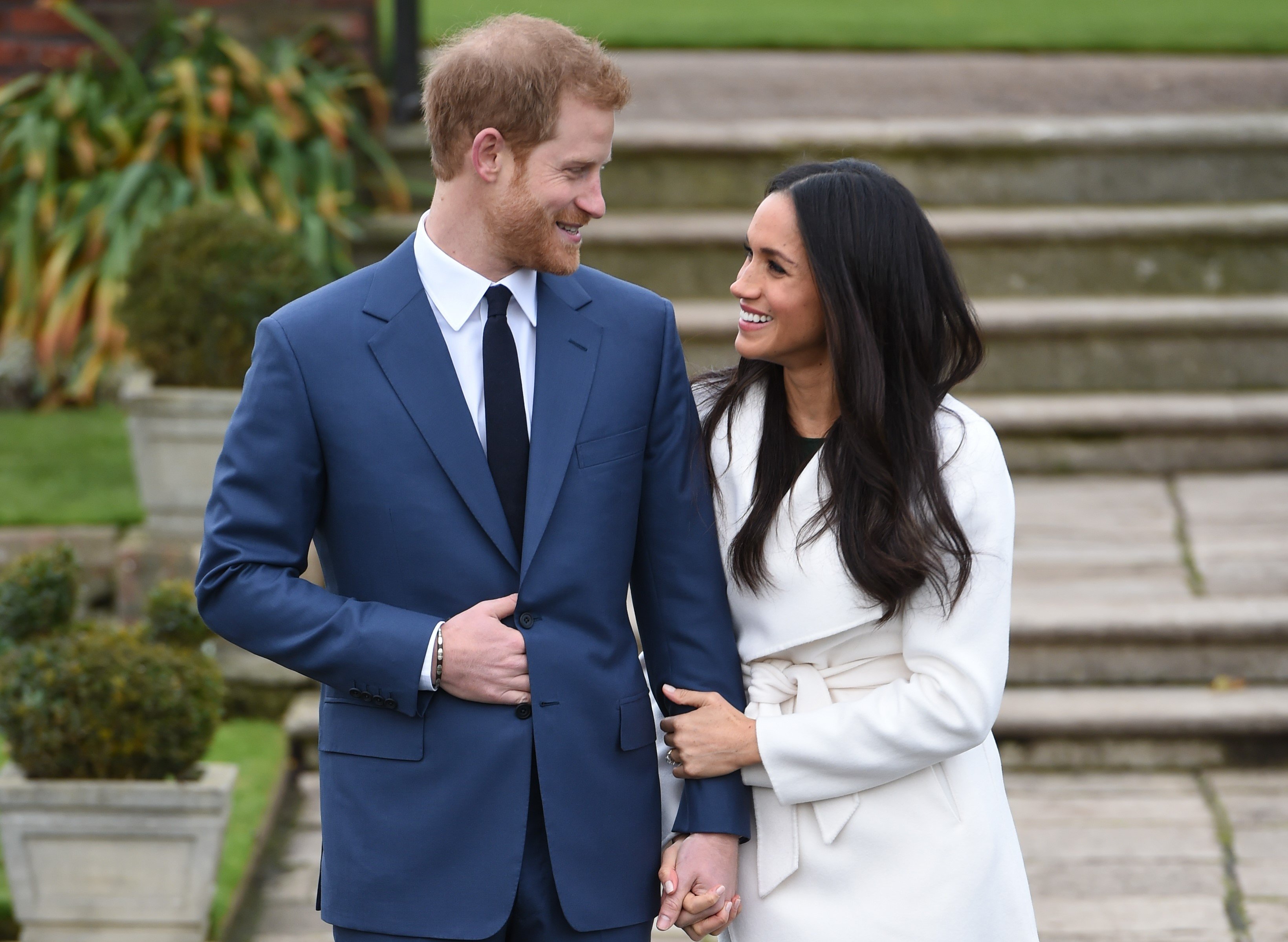 Prince Harry and Meghan Markle holding hands and standing arm-in-arm during photocall