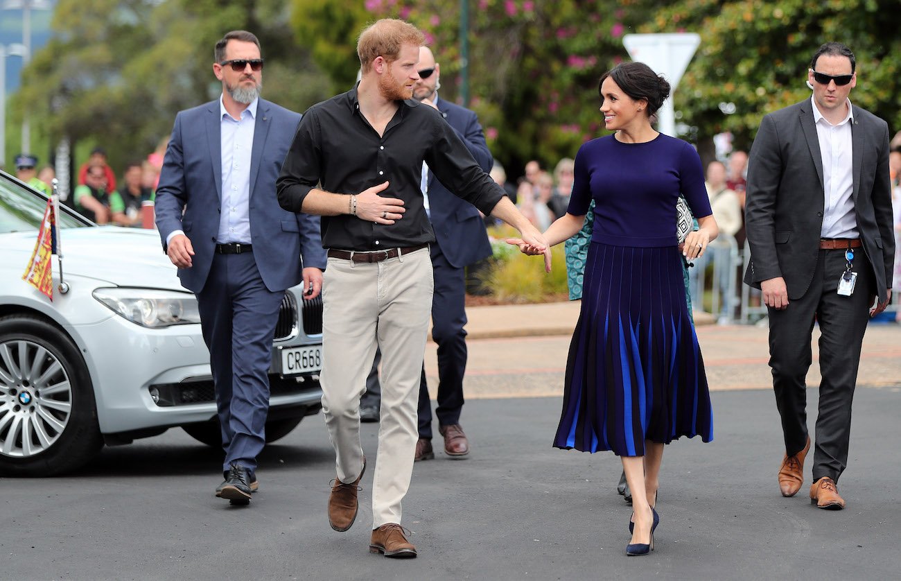 Prince Harry and Meghan Markle hold hands as they walk together