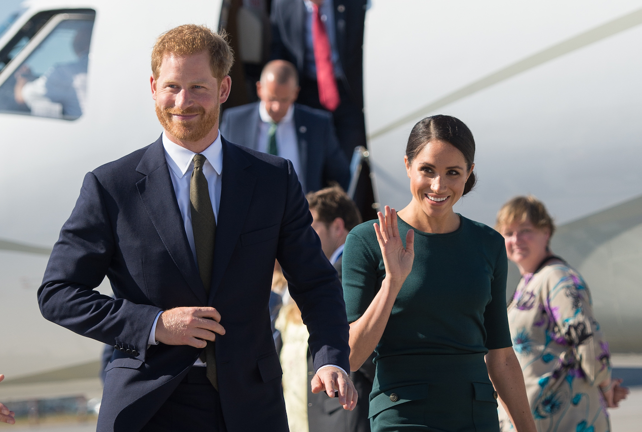 Prince Harry walks in front of Meghan Markle as she waves