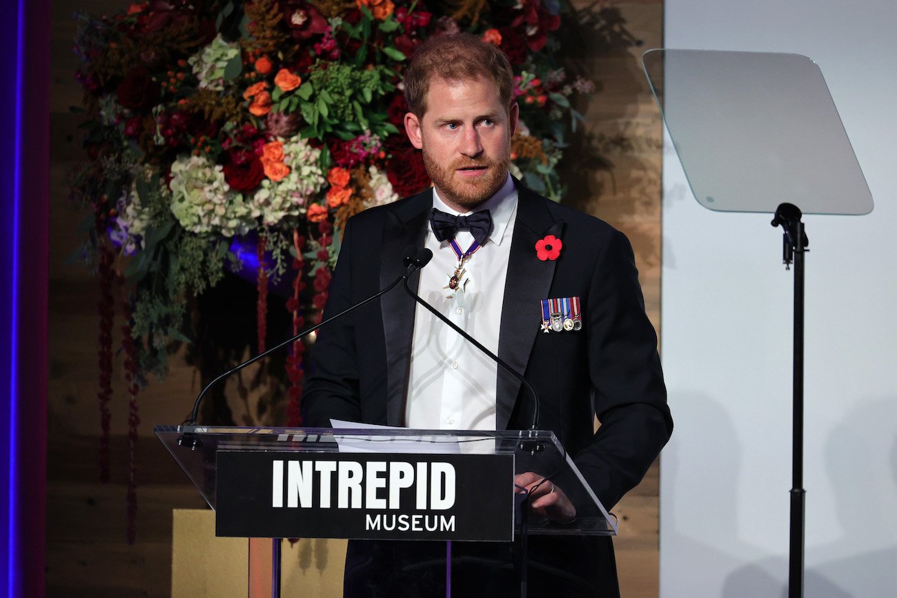 Prince Harry speaks onstage wearing a tuxedo