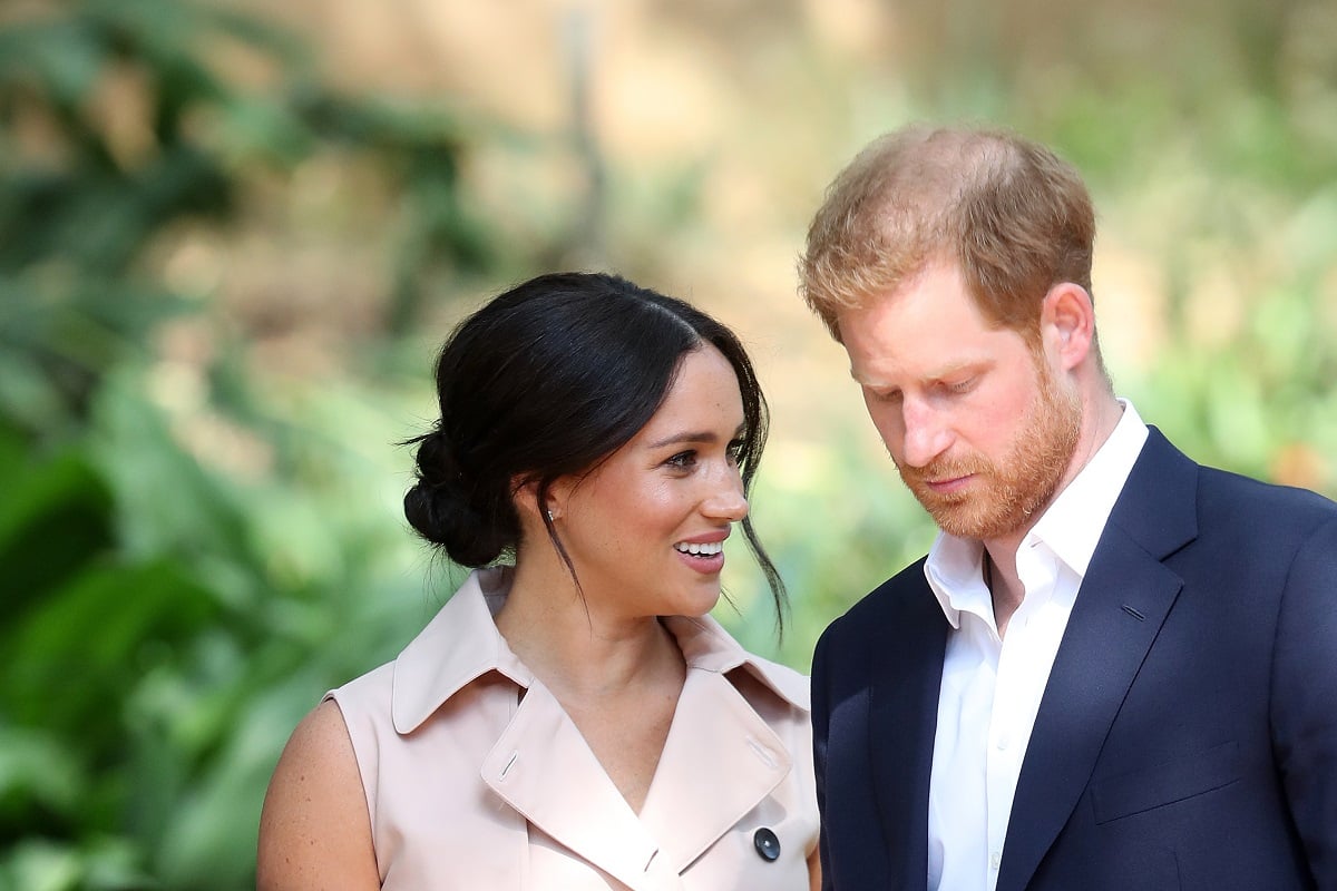 El príncipe Harry mira hacia abajo mientras él y Meghan Markle asisten a una recepción en Sudáfrica.
