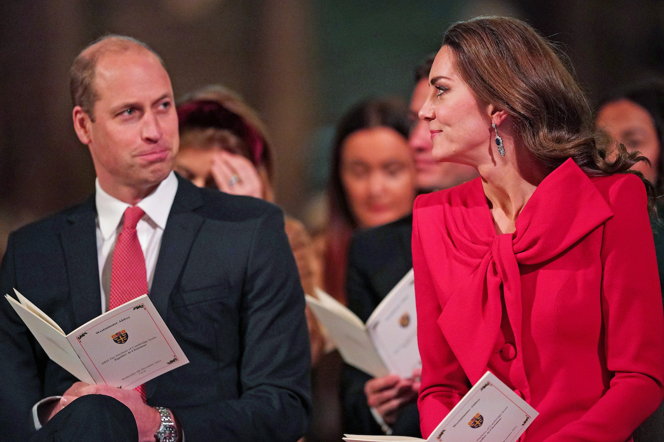 Prince William and Kate Middleton look at each other sitting inside Westminster Abbey