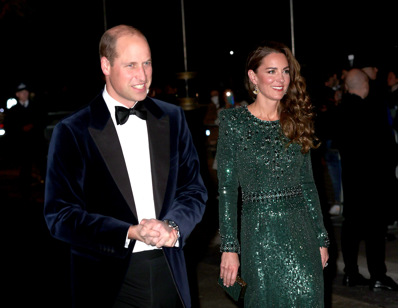 Prince William wears a tuxedo as he walks next to Kate Middleton in a green sequin gown