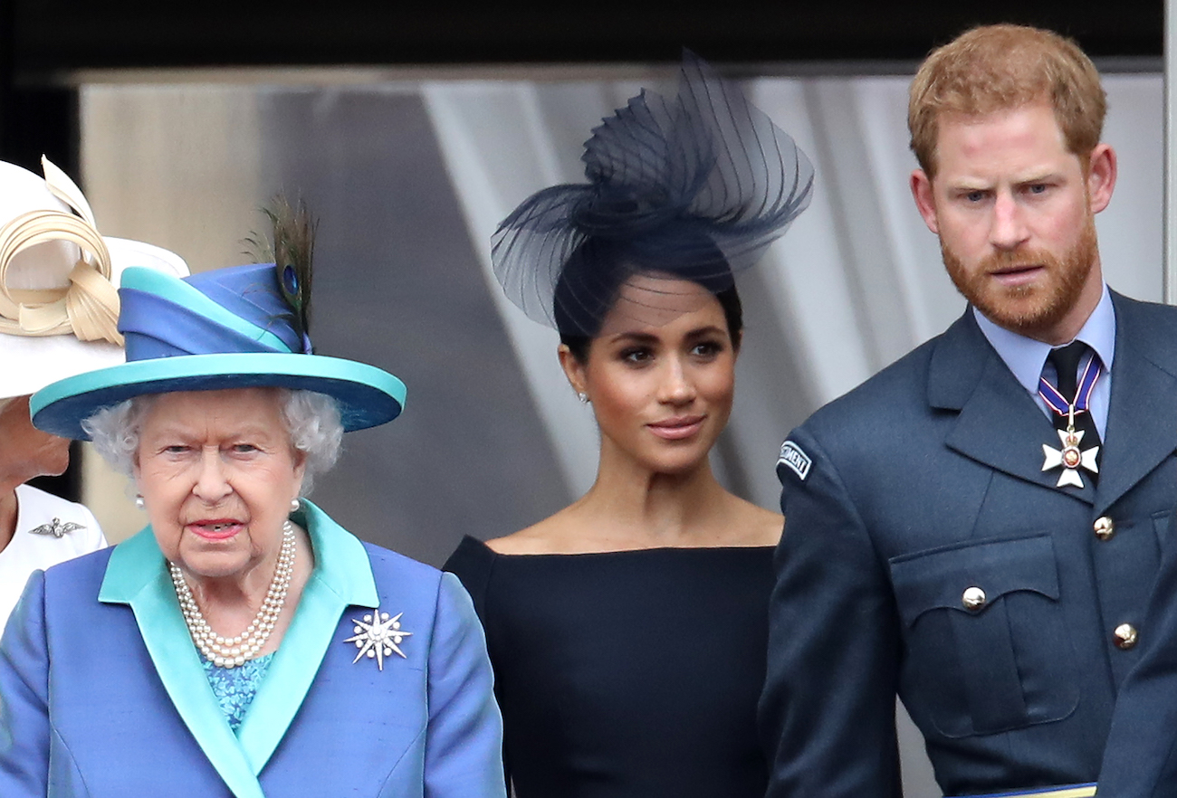 Meghan Markle and Prince Harry standing behind Queen Elizabeth