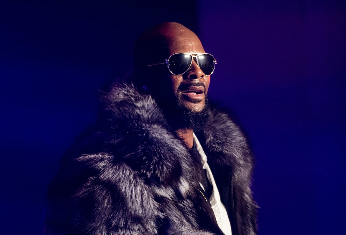 R. Kelly standing on stage in a fur coat