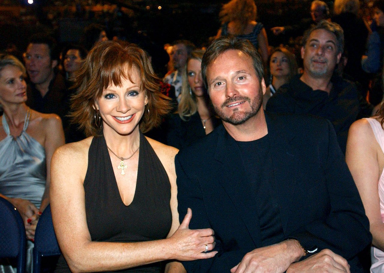 Reba McEntire holds Narvel Blackstock's arm, both seated and dressed in black