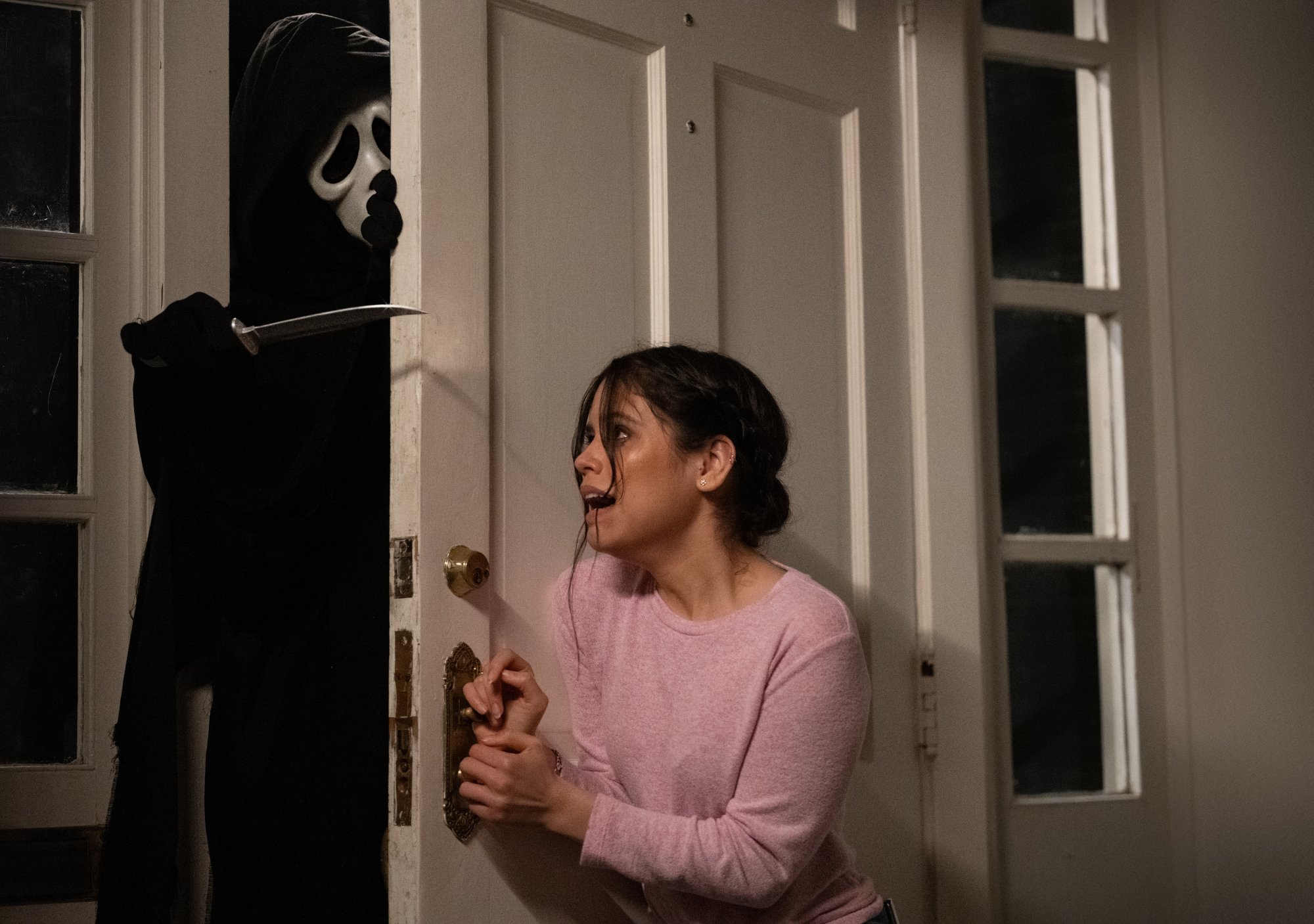 'Scream' movies' Ghostface and Jenna Ortega as Tara Carpenter trying to slam the door against a knife-wielding killer