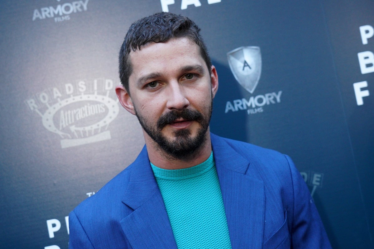 Shia LaBeouf posing while wearing a green shirt and blue blazer.