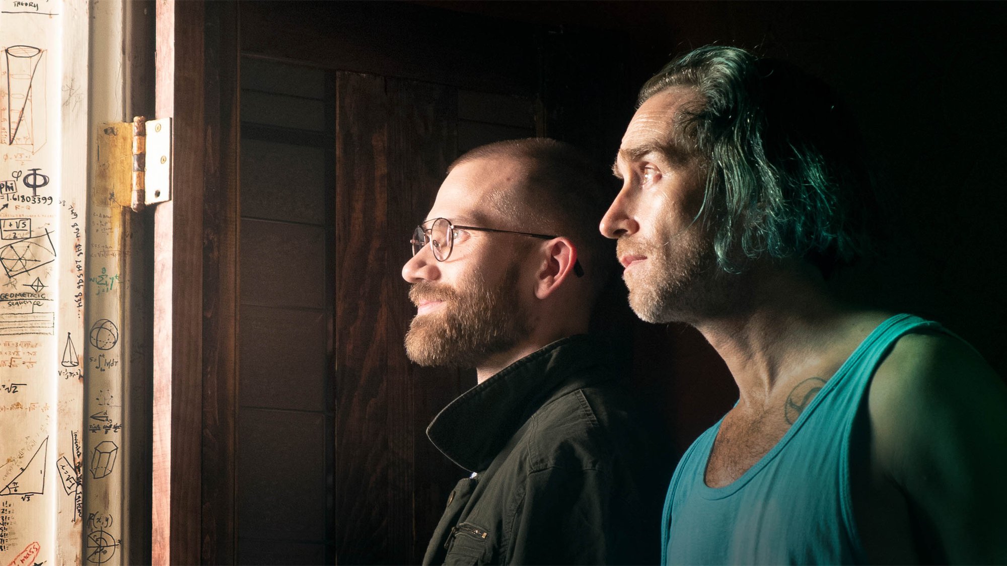 'Something in the Dirt' Aaron Moorhead as John and Justin Benson as Levi looking through a doorway