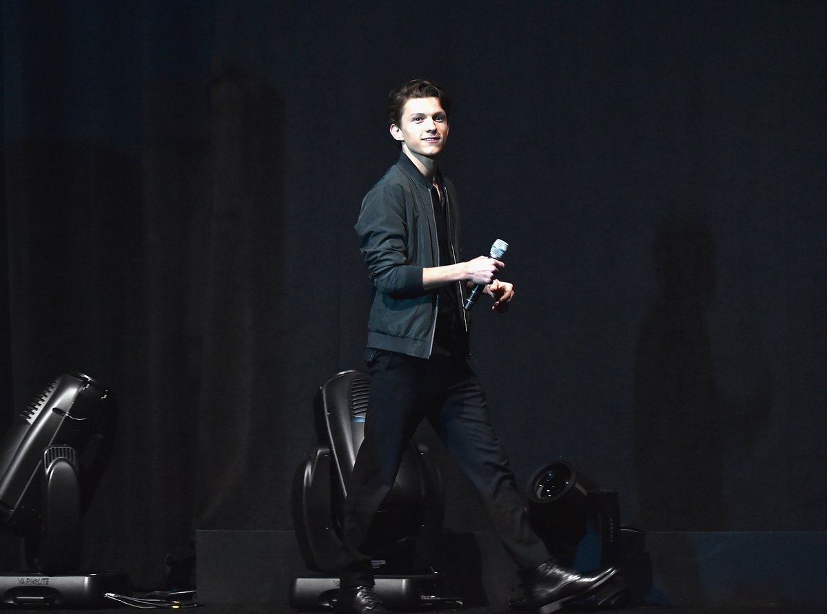 Tom Holland dressed in all black holding a microphone at CinemaCon about a year after his Spider-Man audition got him into 'Captain America: Civil War'