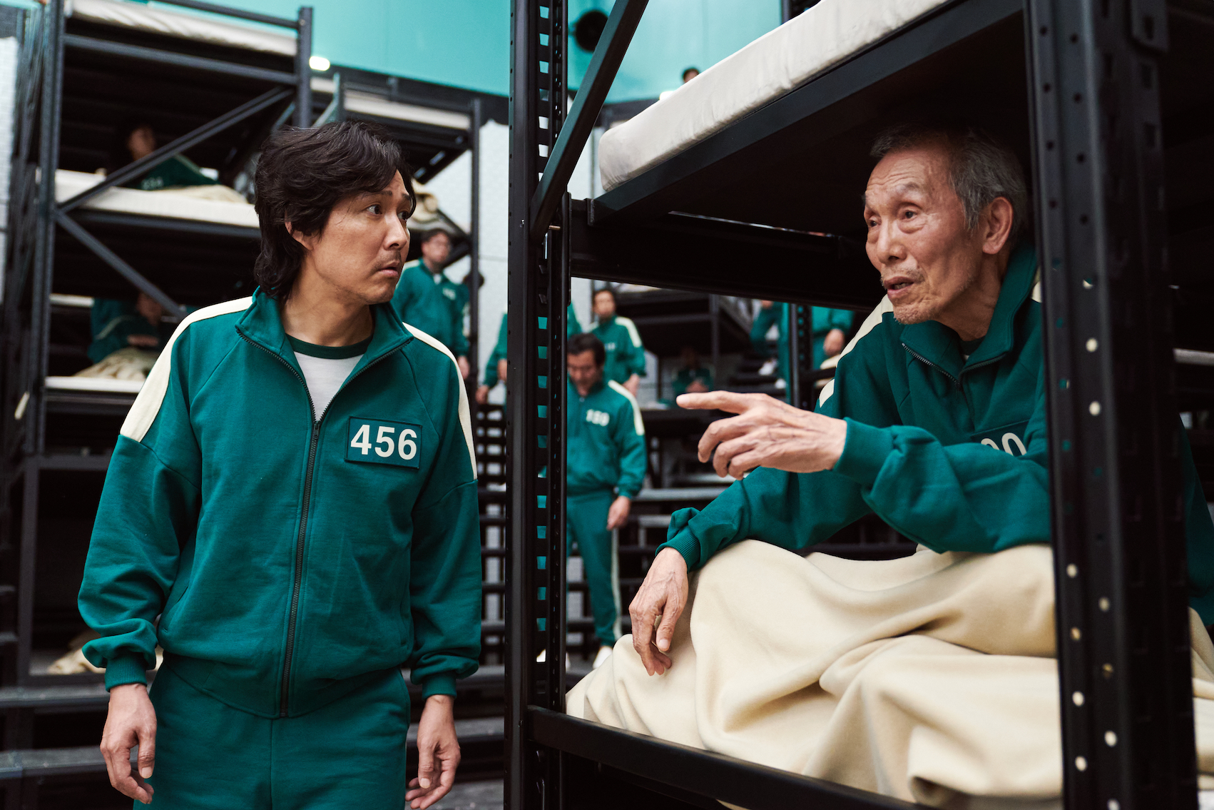 'Squid Game' cast members Lee Jung-jae and O Yeong-su talking while on the set. O Yeong-su is sitting in a bunk bed