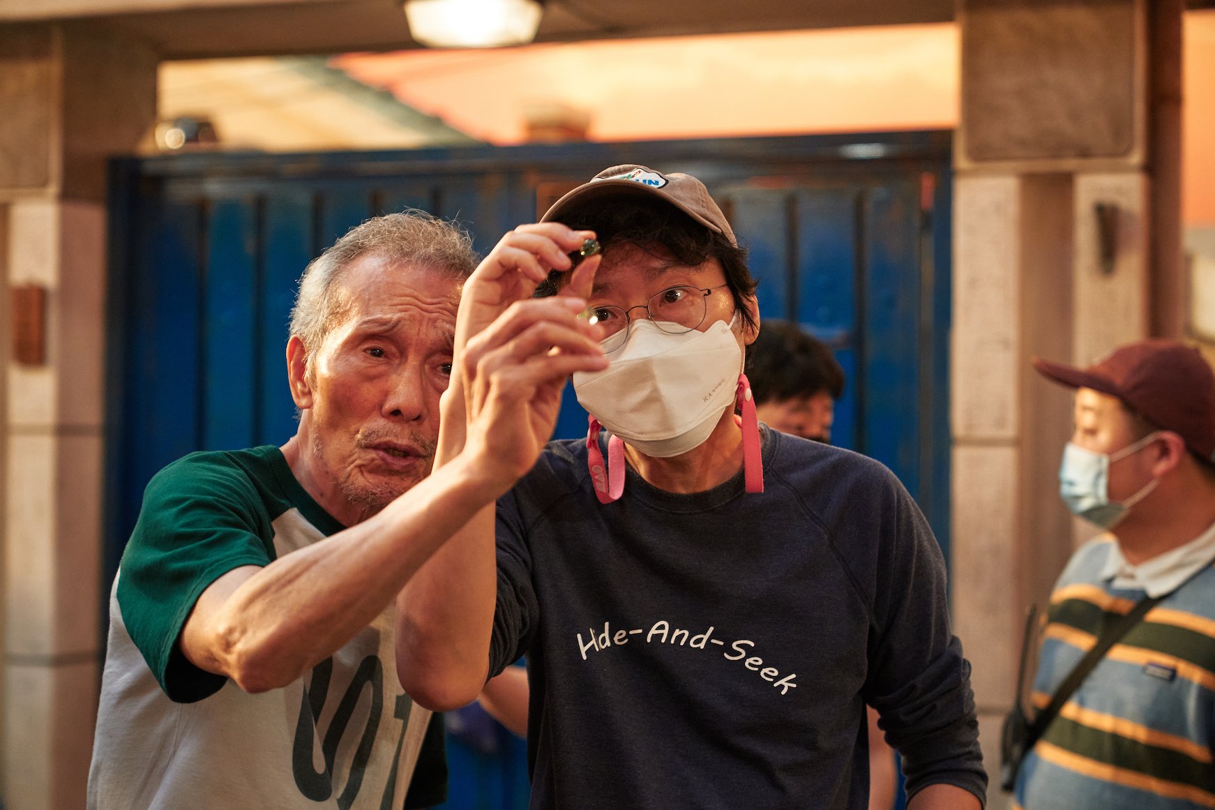 'Squid Game' cast member O Yeong-su with director Hwang Dong-hyuk looking at marbles very carefully