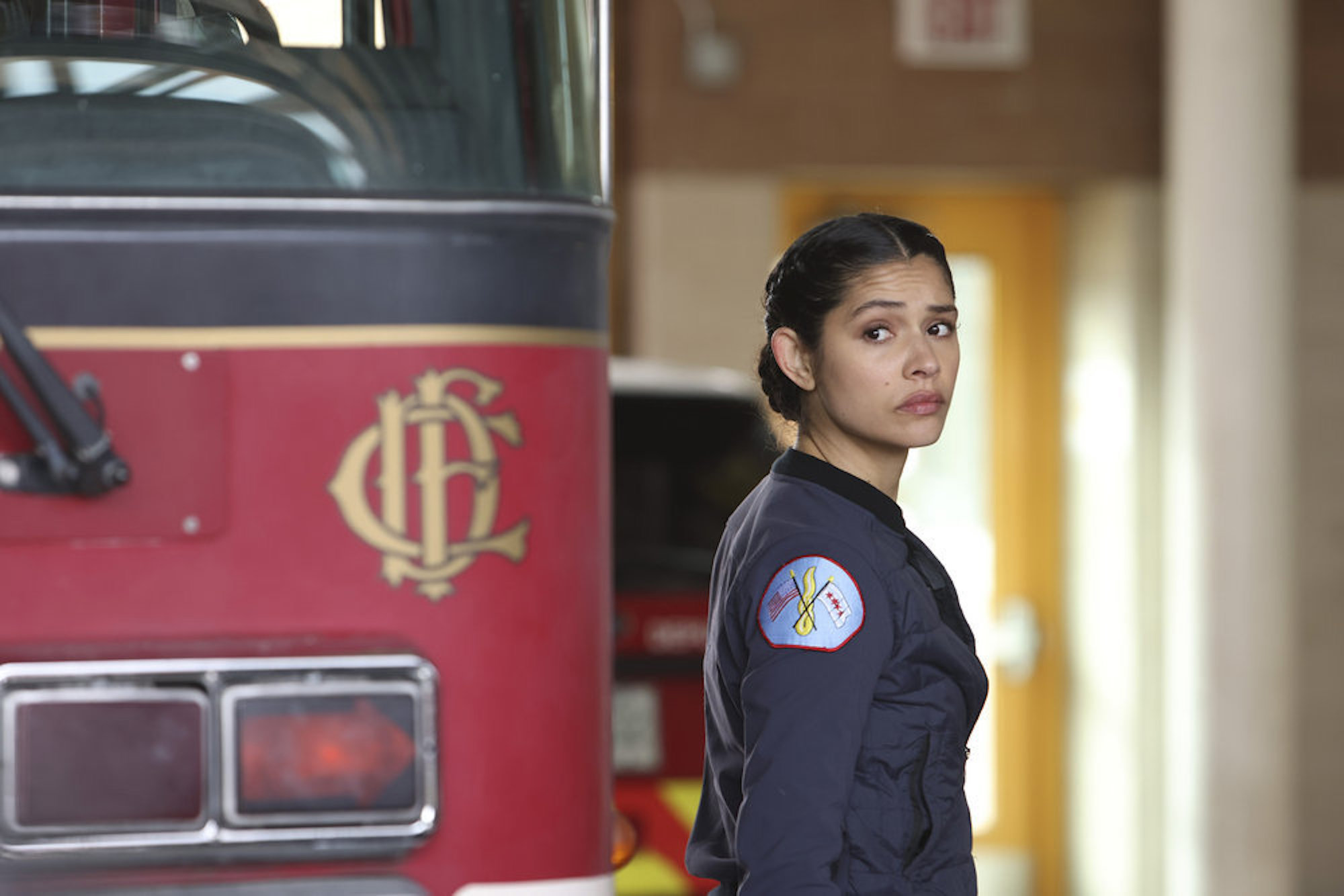 Stella Kidd in uniform next to a firetruck looking over her shoulder in 'Chicago Fire' Season 10