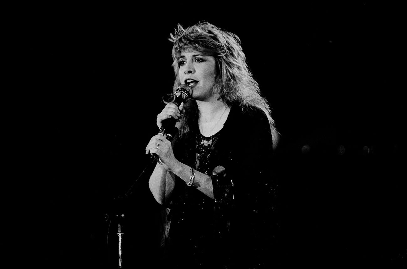 A black and white photo of Stevie Nicks holding a microphone.
