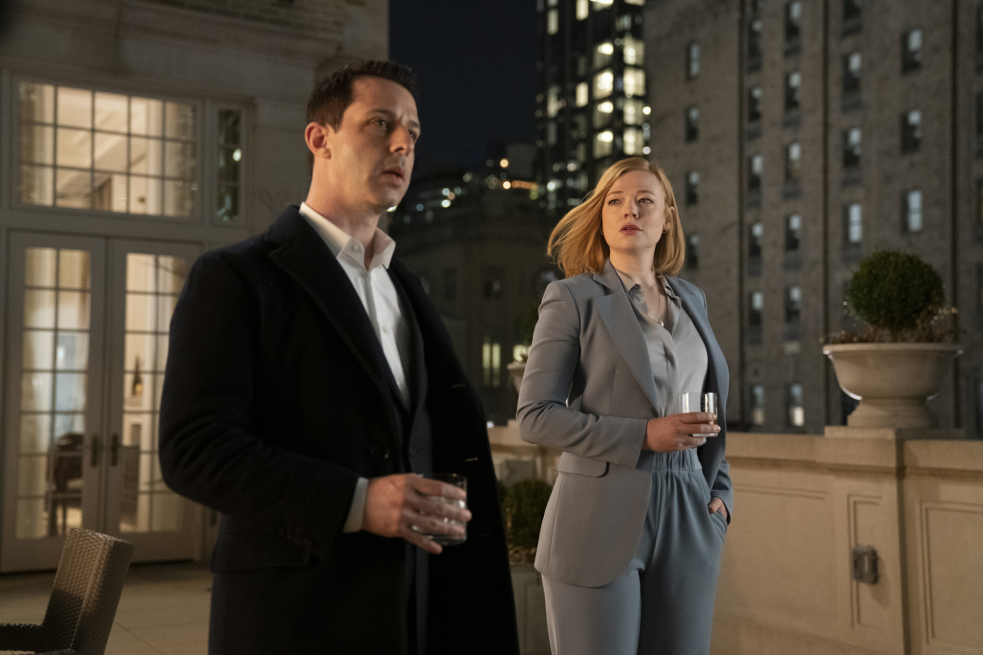 Jeremy Strong and Sarah Snook as Kendall and Shiv Roy in 'Succession' Season 2 Episode 2. They're standing on a balcony and holding drinks.