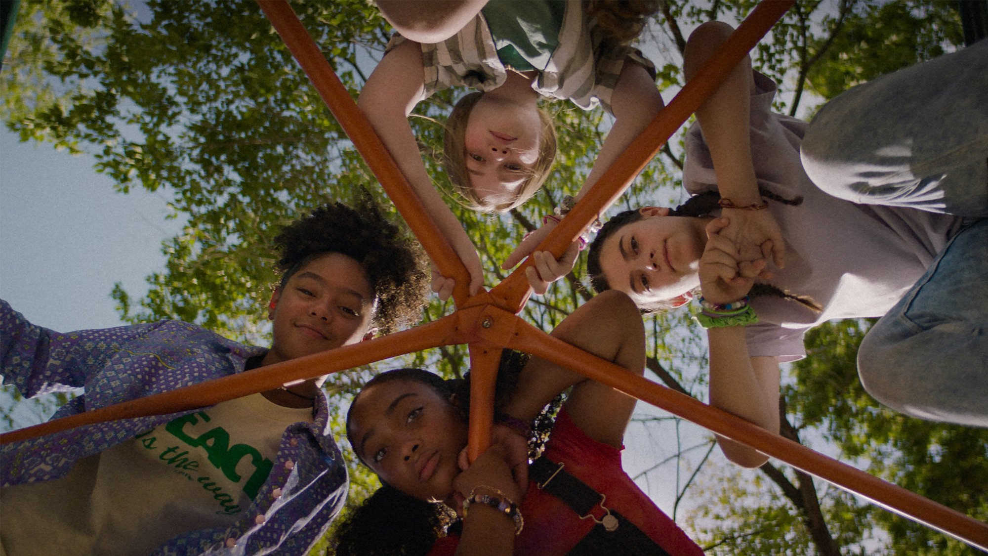 'Summering' Madalen Mills as Dina, Sanai Victoria as Lola, Eden Grace Redfield as Mari, and Lia Barnett as Daisy looking down with trees in the background
