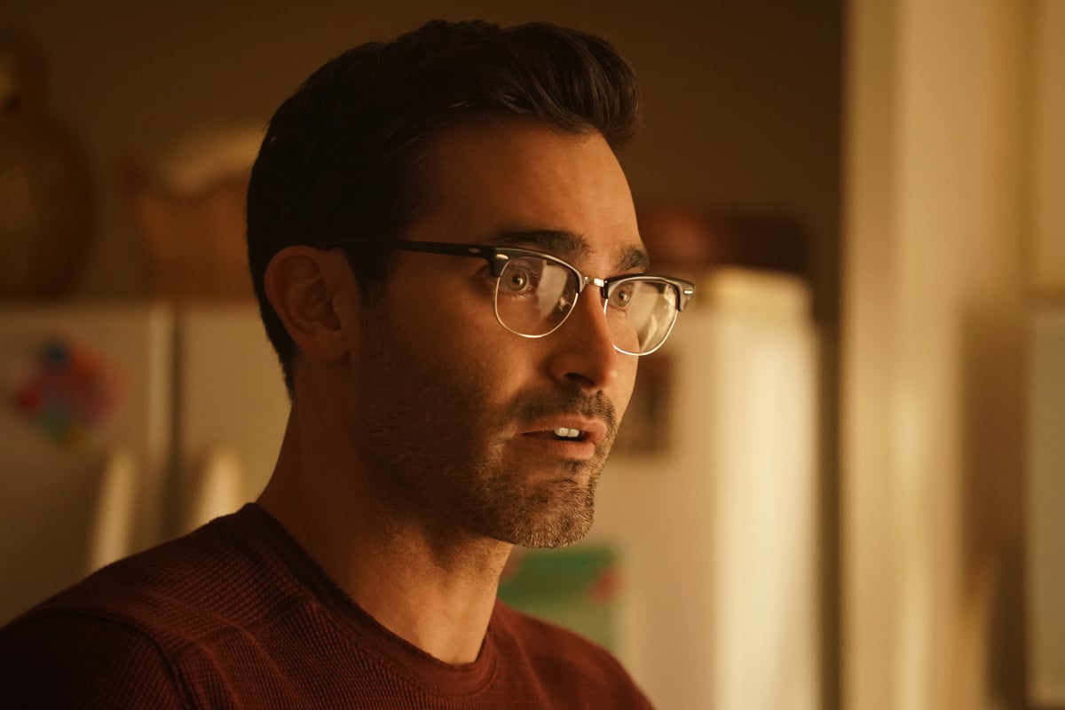 'Superman & Lois' Season 2 cast member Tyler Hoechlin, in character as Clark Kent, wears a red shirt and glasses.