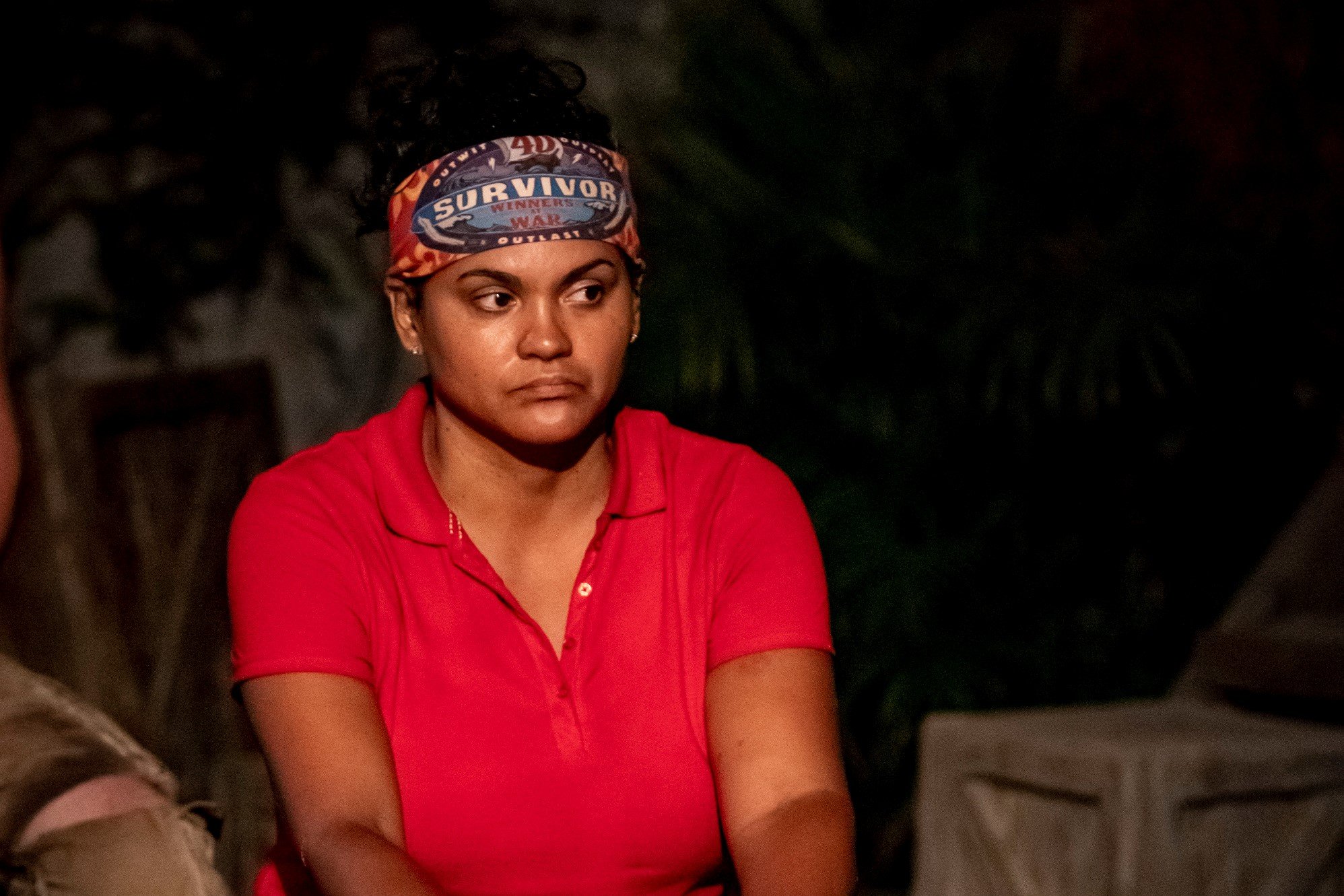 'Survivor' winner Sandra Diaz-Twine wears a red shirt and a red 'Survivor' bluff on her head.