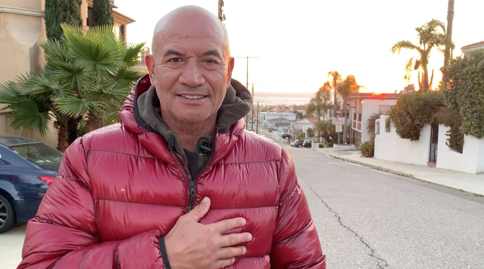 'The Book of Boba Fett' star Temuera Morrison. He's wearing a red winter jacket and holding his hand to his chest.