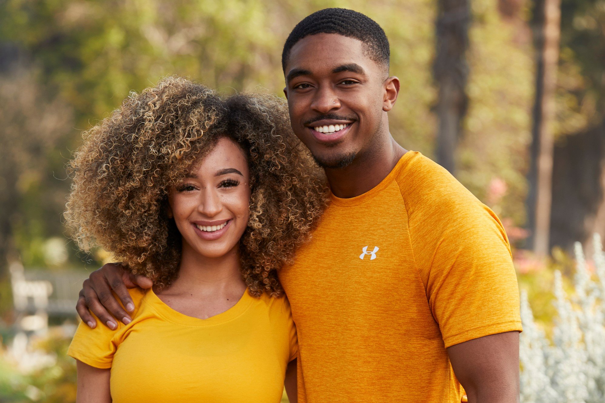 'The Amazing Race' Season 33 stars Caro Viehweg and Ray Gantt pose for promotional pictures. They both wear yellow shirts.