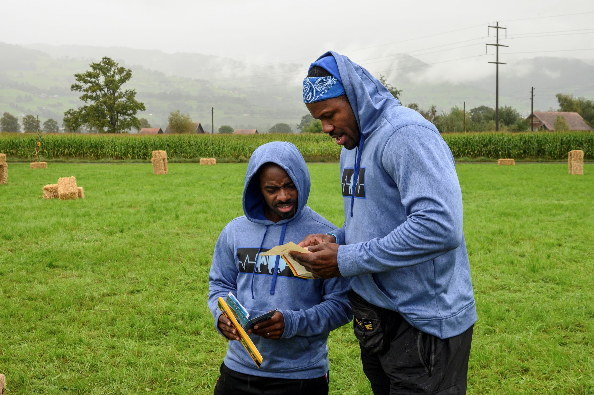 'The Amazing Race' Season 33 contestants Moe Badger and Michael Norwood compete in a leg. They both wear light blue hoodies and black pants as they read a clue.