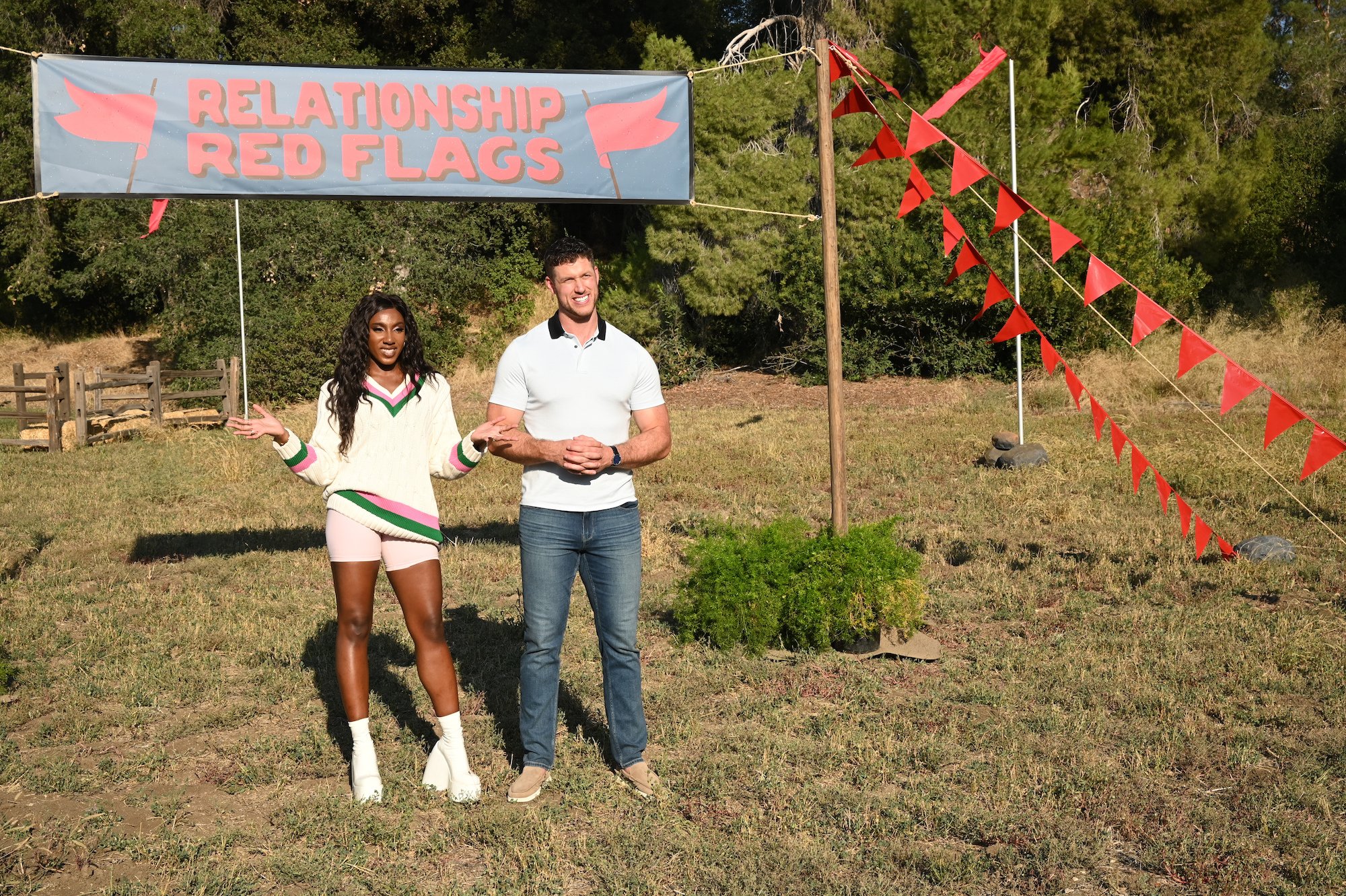 'The Bachelor' 2022 star Clayton Echard standing under a sign that says 'Relationship Red Flag' with Ziwe Fumudoh