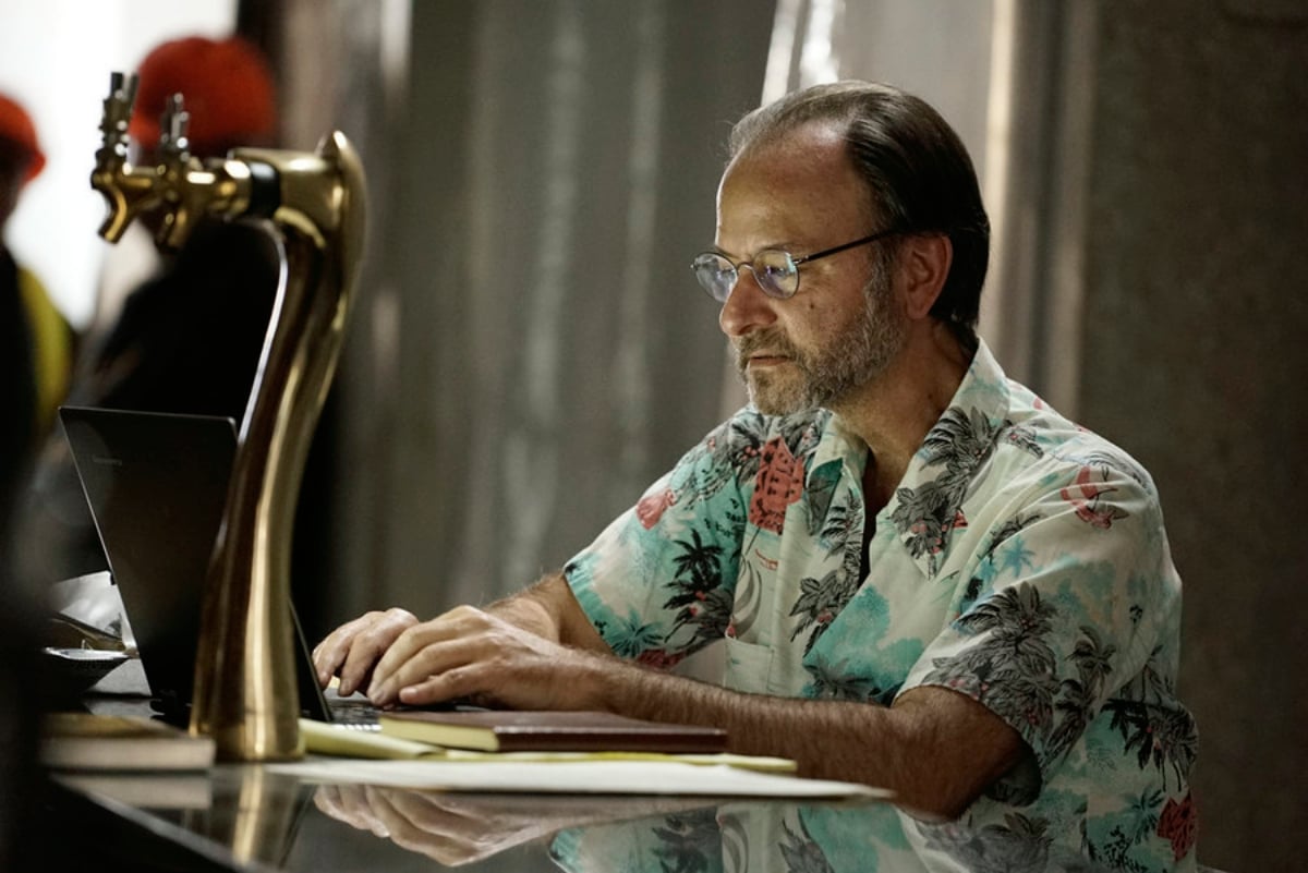 Fisher Stevens as Marvin Gerard in The Blacklist. Marvin sits at a desk and wears a Hawaiian shirt and glasses.