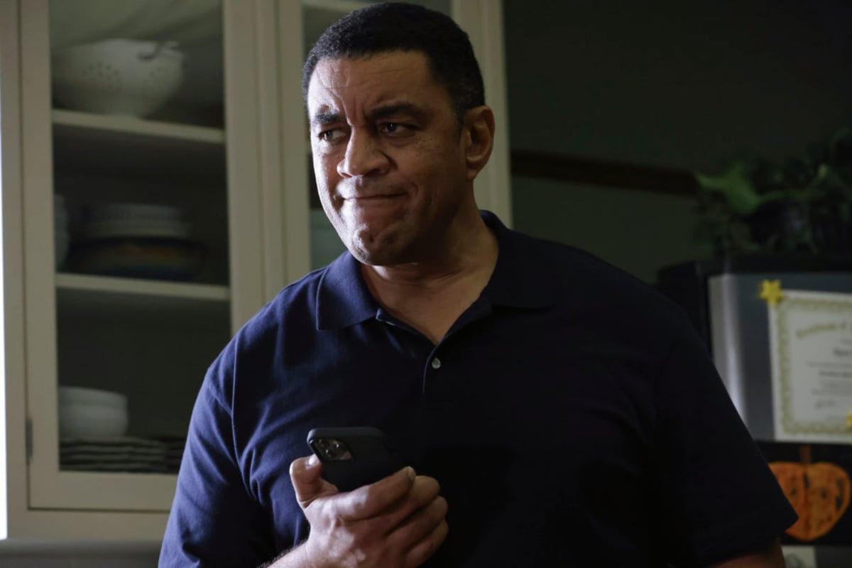 Harry Lennix as Harold Cooper in The Blacklist Season 9. Cooper holds his cellphone and looks concerned.