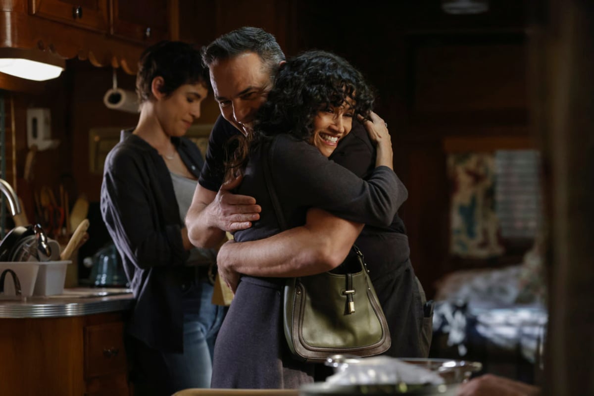 Diany Rodriguez as Weecha Xiu, Ruben Flores as Herman Deleon, Karina Arroyave as Mierce Xiu in The Blacklist Season 9. Mierce hugs a Herman Deleon while Weecha smiles in the background.