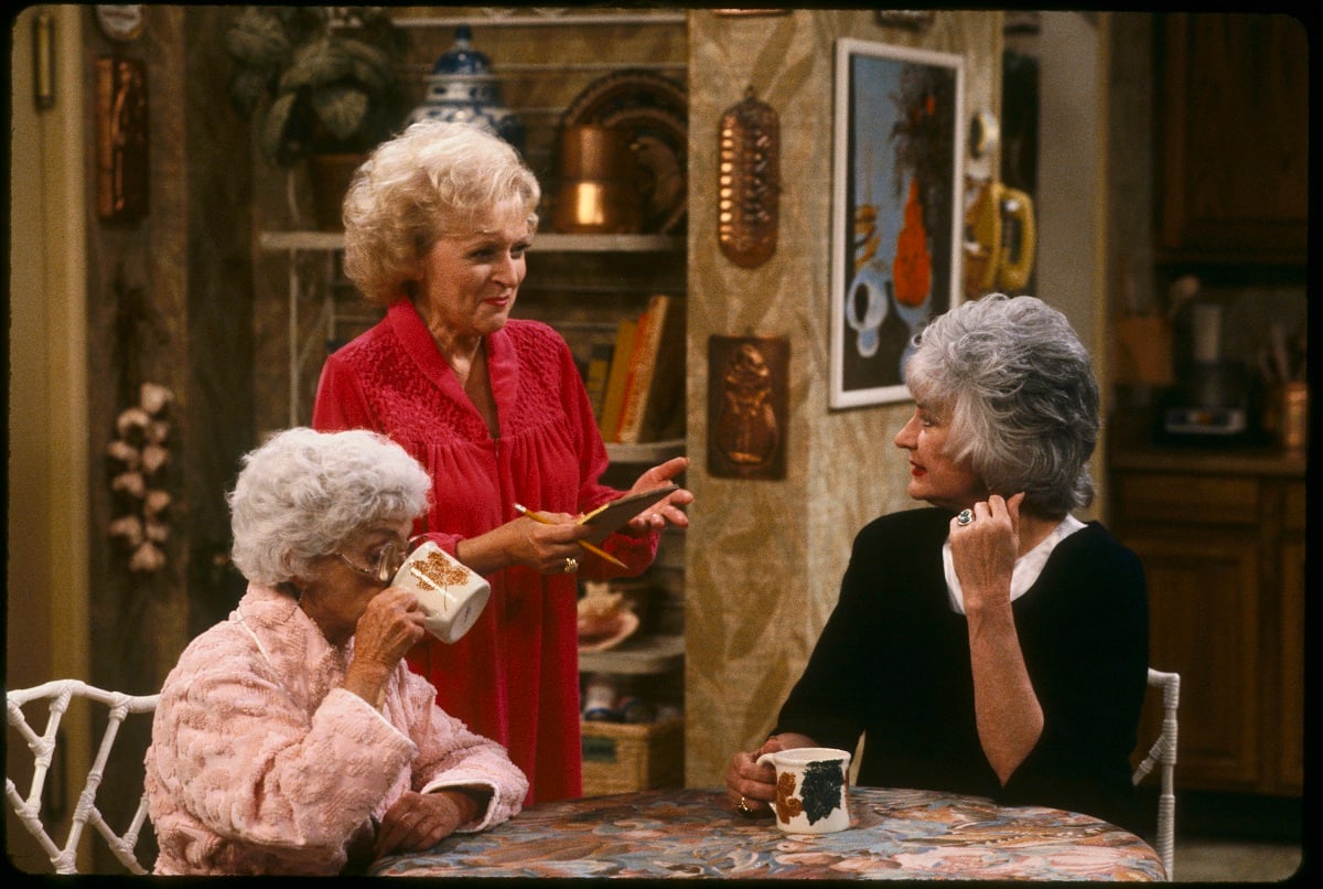 'The Golden Girls' actors Estelle Getty, Betty White, and Bea Arthur; wearing nightgowns and sitting in the kitchen.