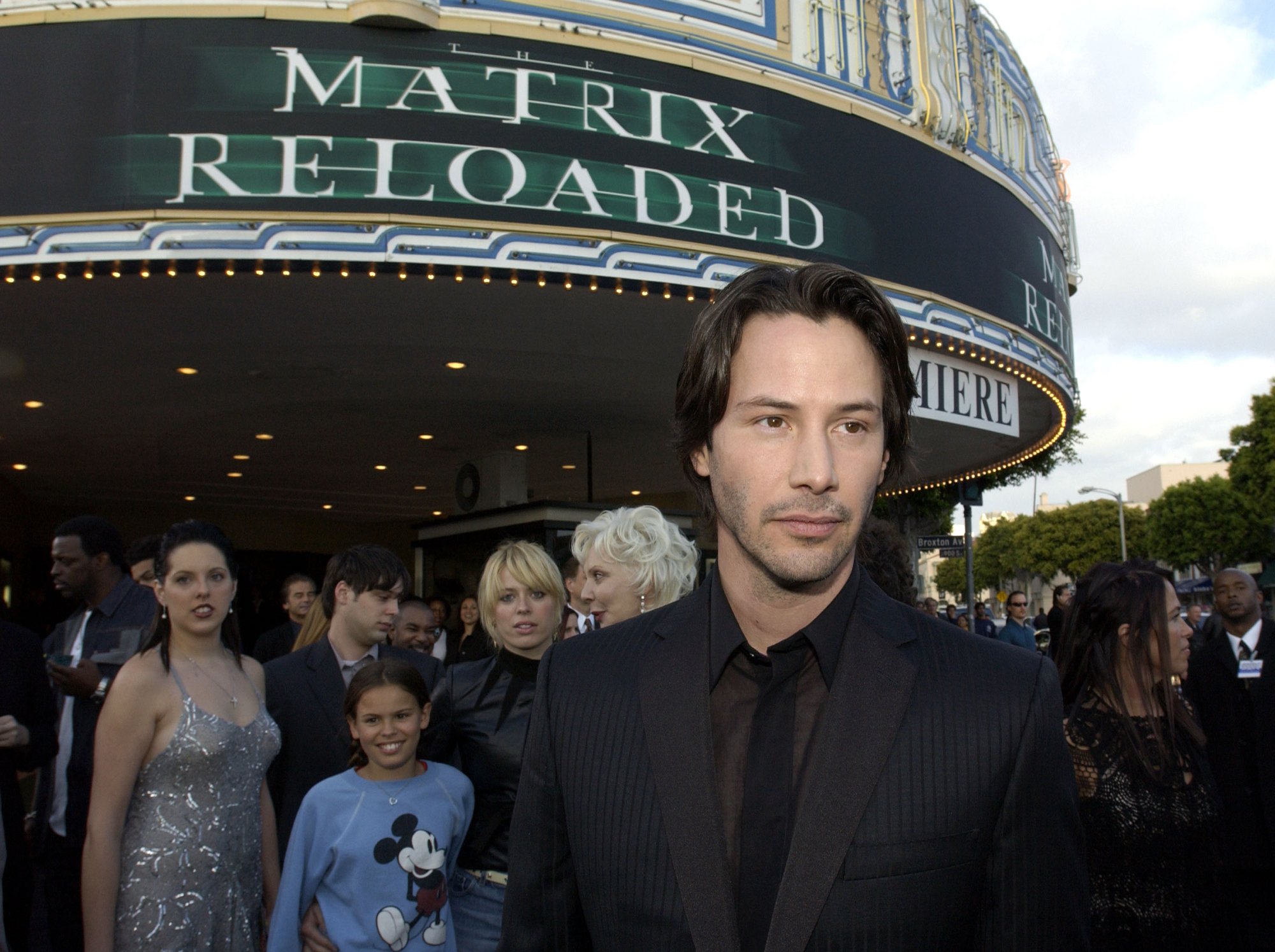 Keanu Reeves standing in front of the 'Matrix Reloaded' sign