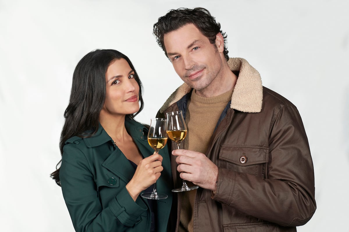 Nazneen Contractor and Brennan Elliott smiling and holding wine glasses in promotional photo for the Hallmark movie 'The Perfect Pairing'