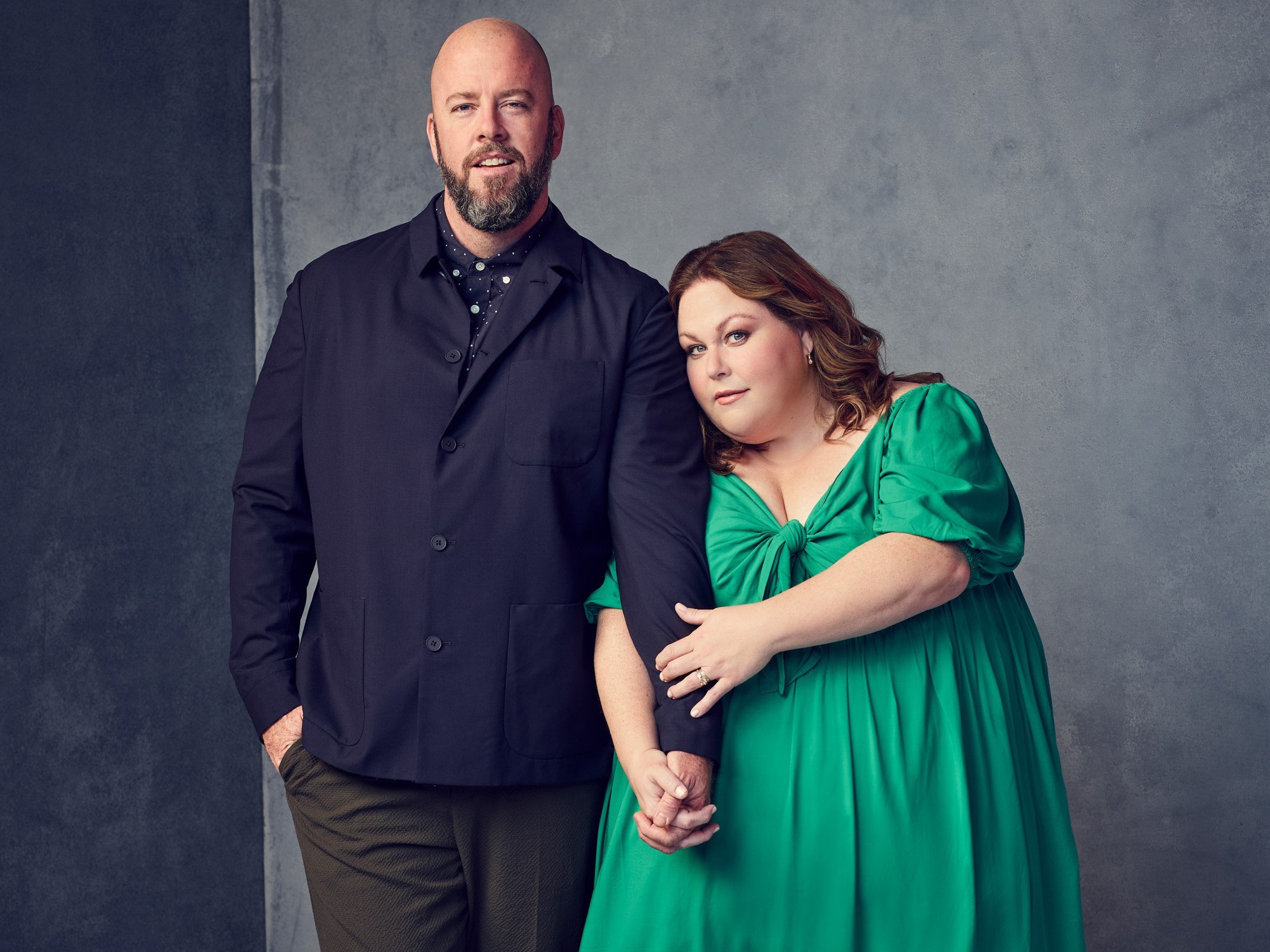 'This Is Us' Season 6 star Chris Sullivan and Chrissy Metz, in character as Toby and Kate, hold hands as they pose for promotional pictures. Sullivan wears a dark blue jacket and gray pants. Metz wears a green dress.