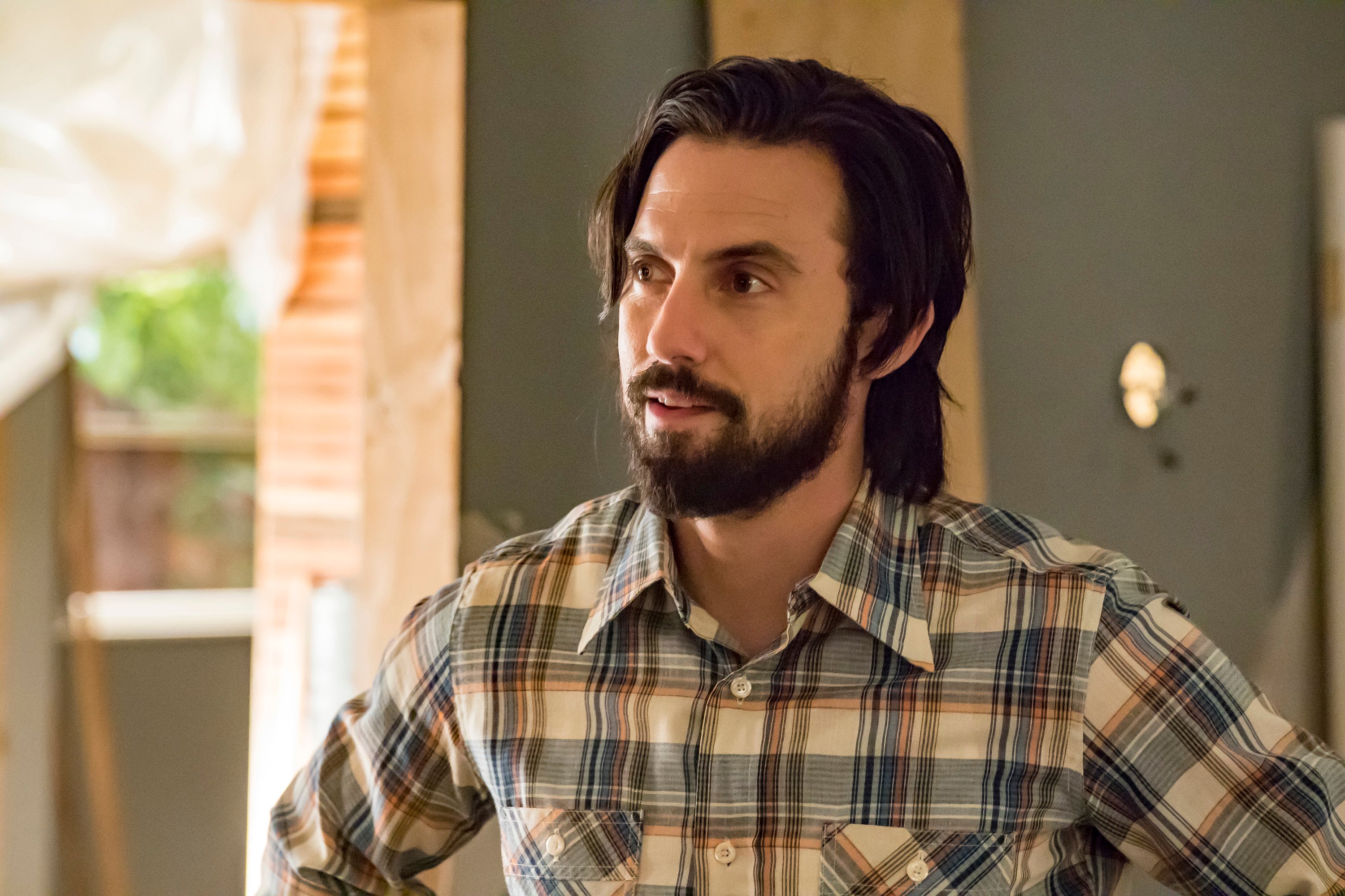 'This Is Us' Season 6 star Milo Ventimiglia, in character as Jack Pearson, wears a blue and white long-sleeved button-up plaid shirt.