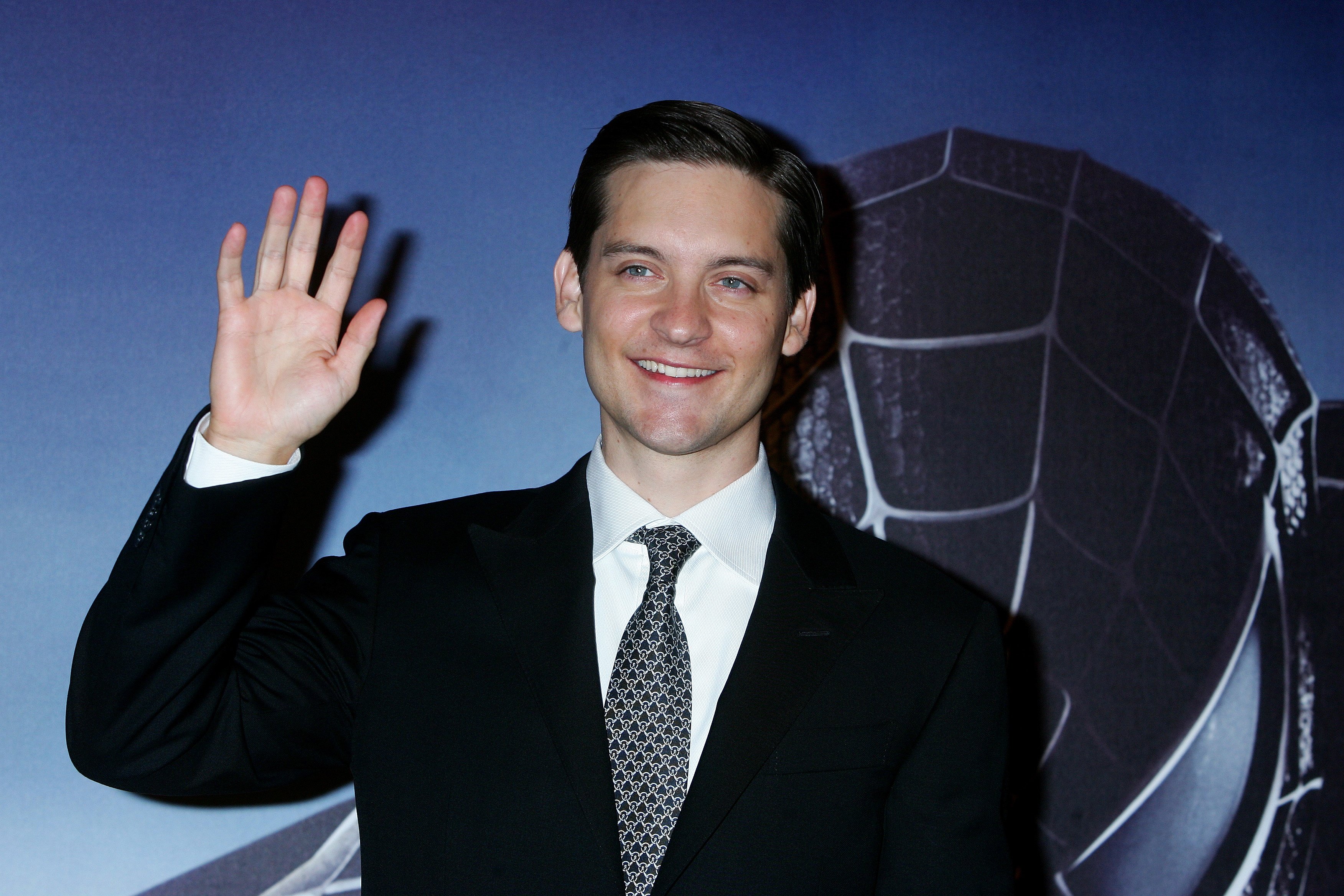'Spider-Man: No Way Home' star Tobey Maguire wears a black suit over a white button-up shirt and black and gray patterned tie.