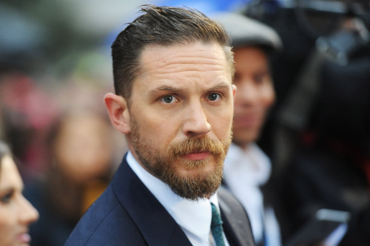 Bane actor Tom Hardy looking serious at a premiere in a suit shown from the shoulders up