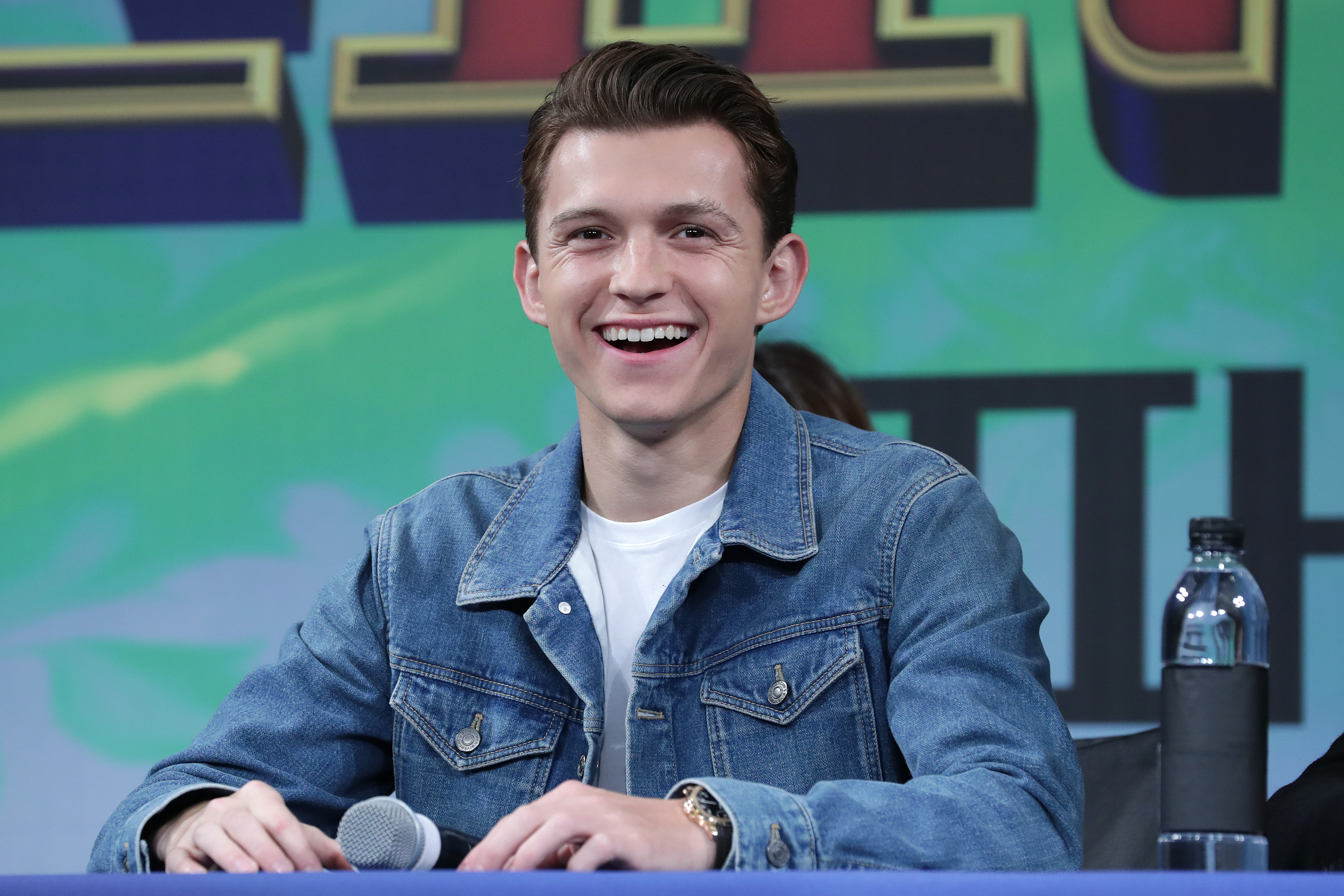 'Spider-Man: No Way Home' star Tom Holland wears a jean jacket over a white shirt.