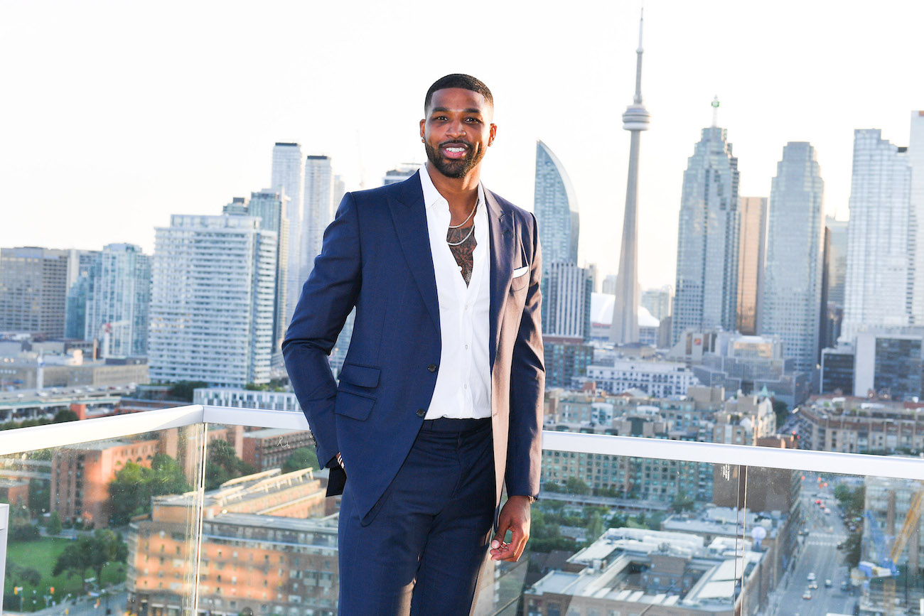 Tristan Thompson wearing a suit and standing in front of the Toronto skyline