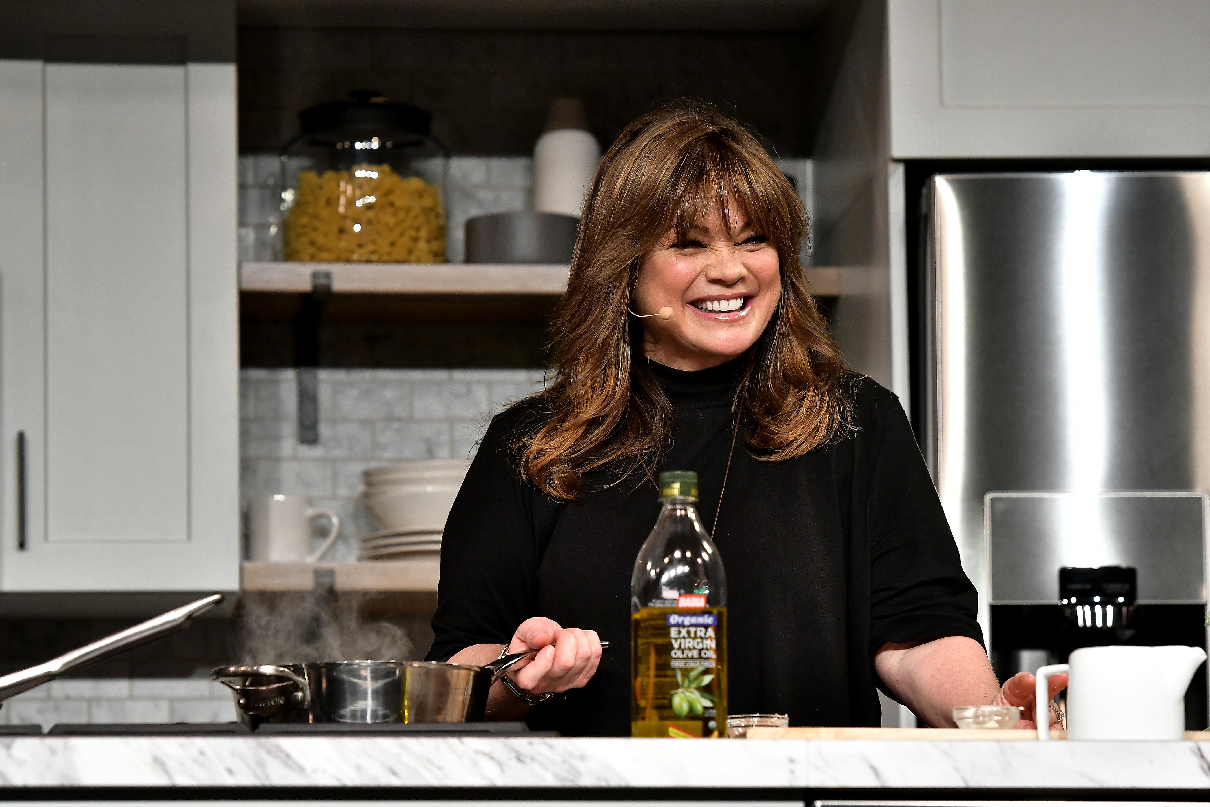 Food Network star Valerie Bertinelli wears a black turtleneck while preparing a meal at a Food Network event.