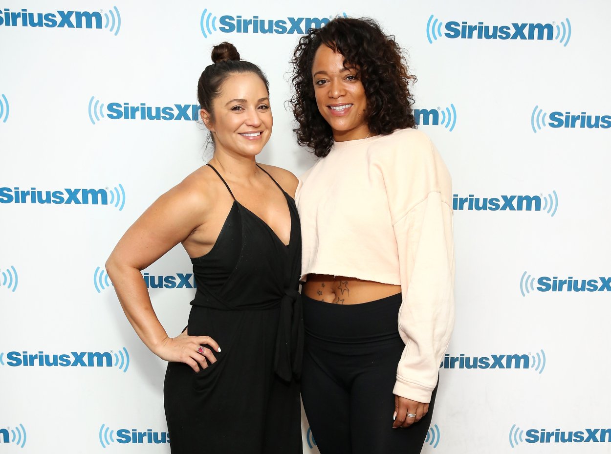 'The Challenge' stars Veronica Portillo (L) and Aneesa Ferreira posing together and smiling while standing in front of SiriusXM Studios backdrop