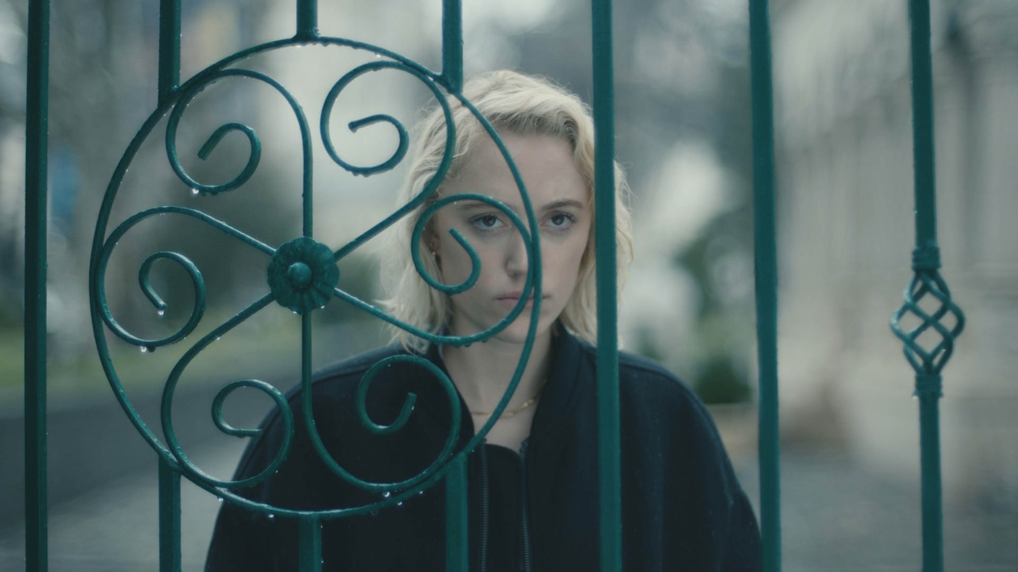 'Watcher' Maika Monroe as Julia standing behind a fence