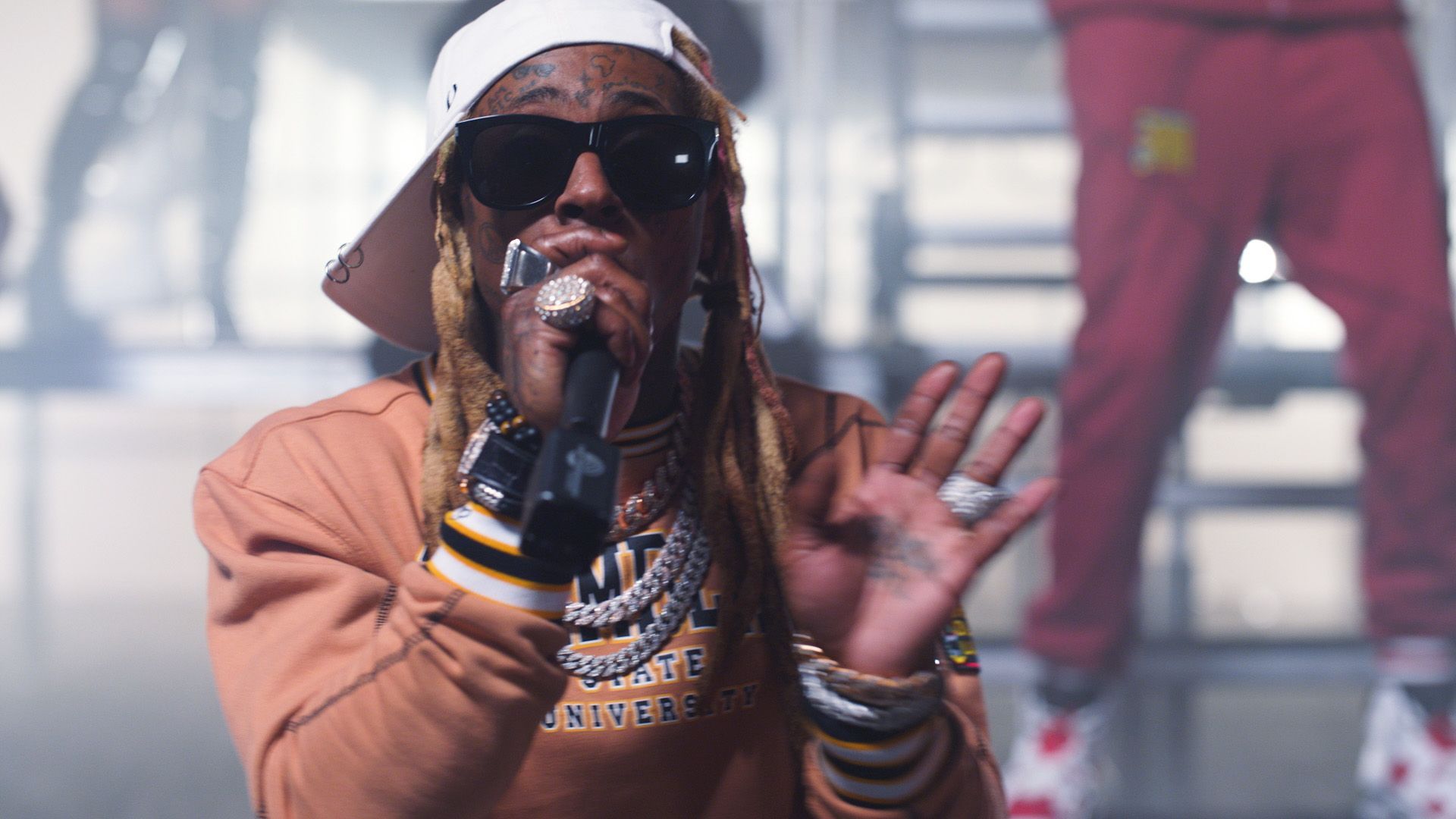 Lil Wayne wearing a white hat and glasses while performing